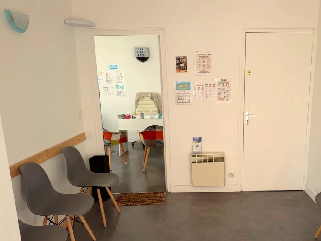 Bureau de consultation, table ronde et chaises dépareillées colorées, où se déroule le premier échange