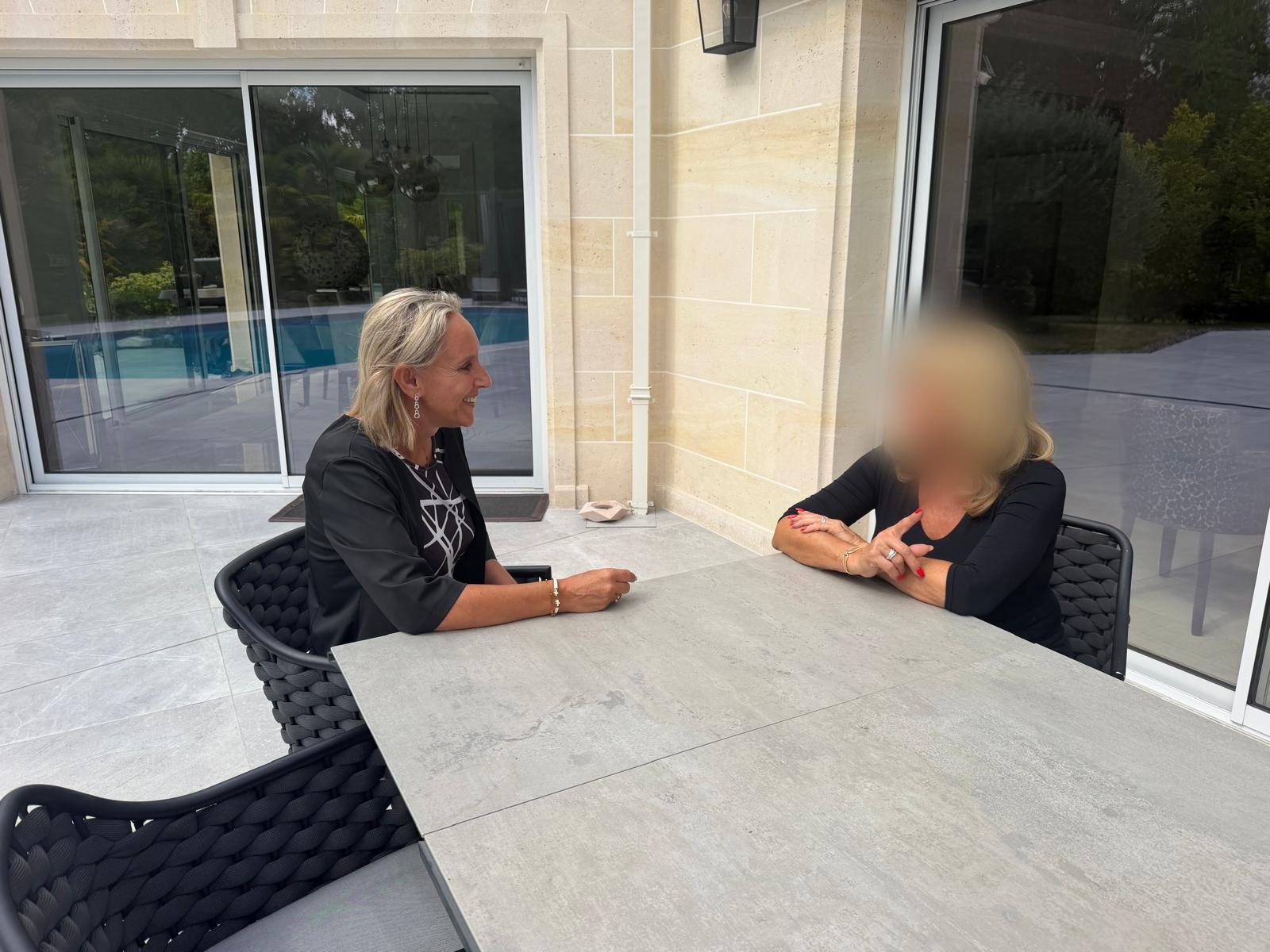 Carole échange avec une adulte autour d’une table ; seul le visage de l’autre personne est flouté