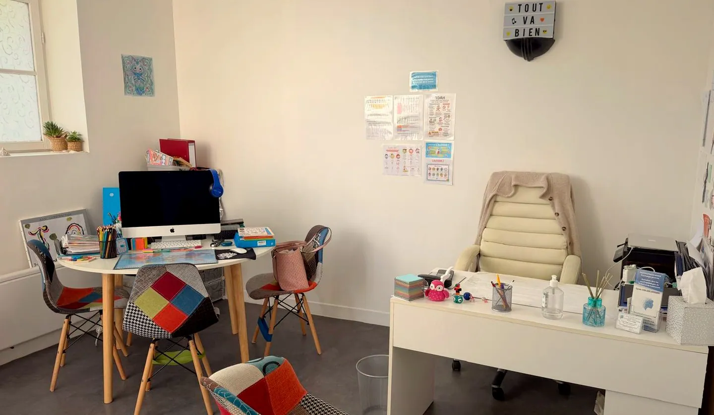 Bureau de consultation, table ronde et chaises dépareillées colorées, où se déroule le premier échange