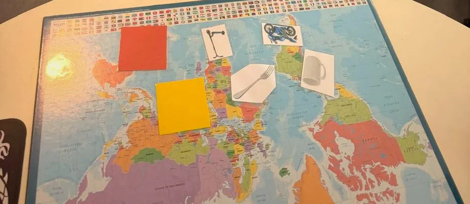 Carte du monde posee sur la table ronde avec cartes images et reperes colores, support de travail sur la memoire